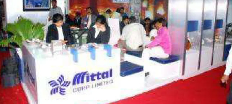 The Mittal Corp Limited exhibition stall, with seating, product displays and visitors in conversation with the team.