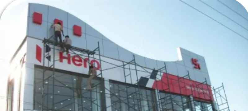 Crew on scaffolding installing new Hero branding across the facade of a motorcycle dealership.