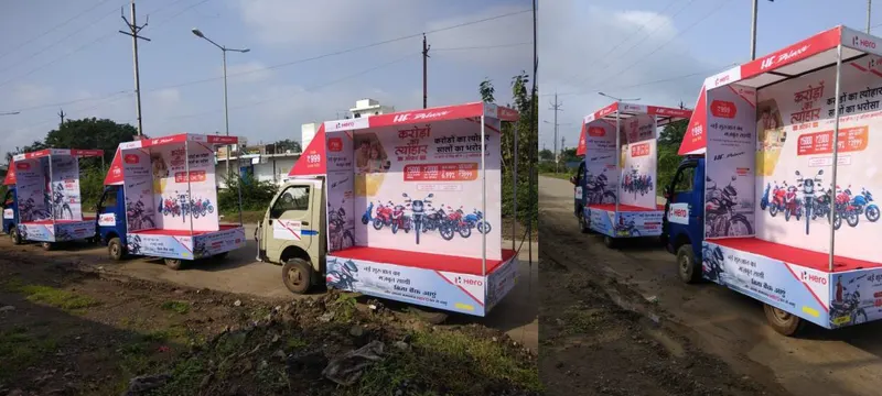 A fleet of Hero branded demo vans parked on a roadside in rural Madhya Pradesh, fitted out to display motorcycles.